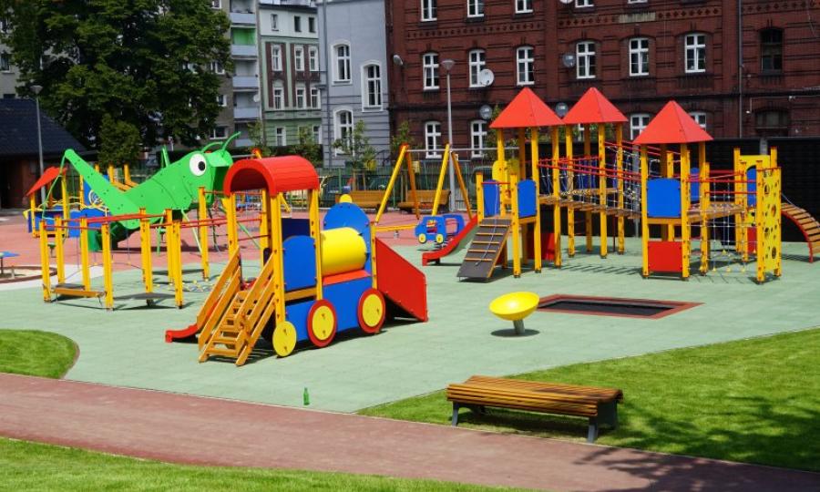 Park Jordanowski, w centrum nowy plac zabawa dla dzieci, w tle budynki